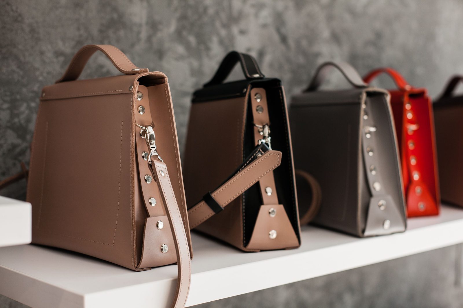 A row of structured leather handbags on a shelf